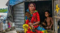 একজন মা ও শিশু বস্তির বাড়িতে সাহায্যের জন্য অপেক্ষা করছে, ২৩-০৪-২০২০।