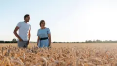 Nadiya and her son Dmytro standing in one of their wheat fields.