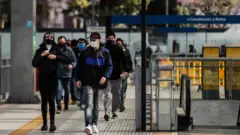 Pessoas andam na rua de máscara em Buenos Aires