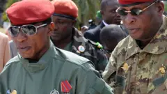 Le chef militaire guinéen, le capitaine Moussa Dadis Camara (G), salue en arrivant, flanqué du général Sékouba Konaté, ministre en charge de la défense nationale, le 2 octobre 2009 à la place des Martyrs de Conakry lors des cérémonies marquant le 51e anniversaire des journées de l'indépendance