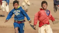 Children running the the sands of Kassala. One child can be seen laughing in the background.