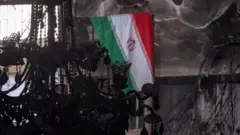 يرفرف العلم الإيراني على جدار المسجد الأقصى، الذي احترق خلال الاحتجاجات المناهضة للحكومة في شرق طهران، إيران، في 21 يناير/كانون الثاني 2026. 