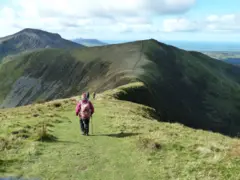 Pessoa caminhando em uma região montanhosa com verdes