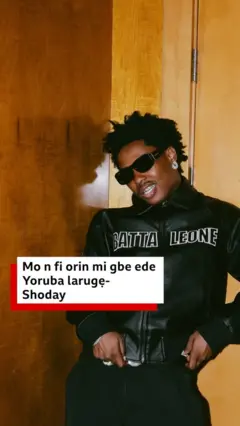 Shodey wọ asọ toke tilẹ dudu, o lo awo oju, o si ta irun rẹ ni koko