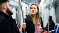Une femme parle à un homme dans une rame de métro.