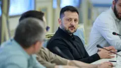 Зеленський сидить за столом з журналістами
