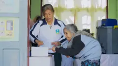 Women stand by ballot boxes at a polling station in Shan state, Myanmar