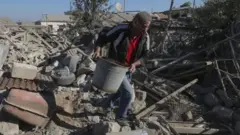 Umugabo ari kwigizayo ibyasenyutse mu murwa mukuru Stepanakert w'akarere ka Nagorno-Karabakh