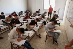 طلاب يؤدون اختبارات نهاية العام الدراسي، فيما يظهر في الصورة أحد المراقبين داخل لجنة الامتحان.