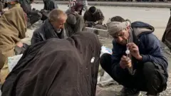 Men gathered on the side of the road in the capital, Kabul to use drugs