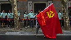 上海中共一大會址紀念館外一位參觀者舉著黨旗走過（17/6/2021）