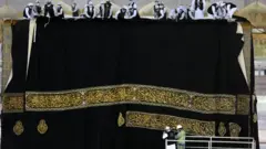 کارګر ورېښمین پوښ کعبه شریفه اچوي. سږ کال د حج مراسم سختو روغتیايي اصولو او کمو خلکو سره وشول.