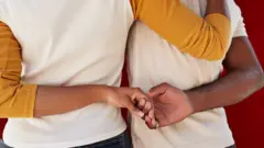 Boy and girl hold hands from back