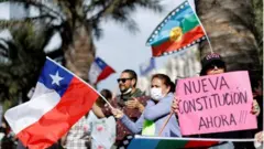 Manifestantes sostienen banderas y carteles