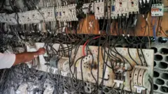فني يتحكم في لوحة مفاتيح كهربائية تربط المنازل بمولدات كهربائية في إحدى ضواحي العاصمة اللبنانية بيروت