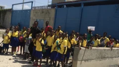 Children in school uniforms in Cité Soleil waiting for a lift