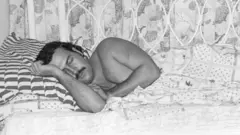 Pablo Escobar endormi avec sa belle-sœur assise sur le coin de son lit.