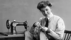 A seamstress using a Singer sewing machine in 1907
