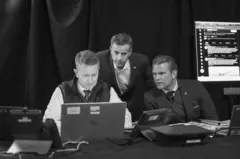 Ratcliffe y Hegseth miran una computadora portátil en la que trabaja un funcionario.