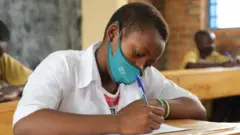 Umunyeshuri w'umukobwa urimo gukora ikizamini cya leta mu Rwanda ku itariki ya 12 y'ukwezi kwa karindwi mu 2021