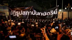 Pro-democracy demonstrators stand in front of a banner reading: "Reform the monarchy" during a protest, in Bangkok, Thailand October 26, 2020.