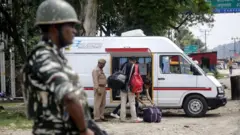 An Indian security forces personnel stands guard as Kashmir police men check luggage