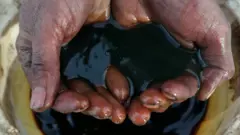 Crude oil pouring through a man's hand