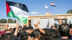 Sejumlah relawan dari berbagai organisasi kemanusiaan menyerukan yel-yel di depan pintu perbatasan Rafah di Mesir. Mereka menyerukan agar pintu perbatasan dibuka agar bantuan bisa dikirim ke Gaza.