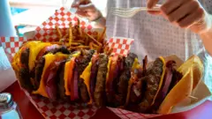 A huge stacked burger and fries