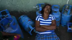 Seorang perempuan tidur saat mengantri untuk mengambil tabung Liquefied Petroleum Gas (LPG) di titik distribusi di Kolombo pada 12 Juli 2022.