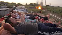 Migrants workers from Tajikistan relax on the roof of their shelter after working at local market outside Moscow, July 18 2011