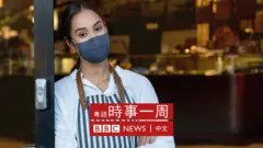 一位女服務員戴著口罩站在餐廳門口