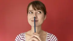 Una mujer con un lápiz pensando.