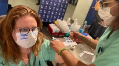 Adriana, com máscara com bandeira de Israel, recebe vacina