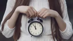 Una mujer sostiene un reloj en su vientre.