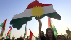 Una mujer sosteniendo un mapa con la bandera de Kurdistán.