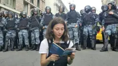 Olga Misik reads constitution as dozens of riot police stand behind her