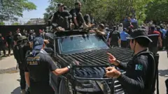 أفراد أمن يرافقون سيارة تقل رئيس الوزراء الباكستاني السابق عمران خان أثناء وصوله إلى المحكمة العليا في إسلام أباد في 9 مايو/أيار 2023.