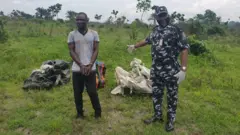 One of di kidnap suspect, Friday Akpan with Police tok tok pesin, Nnamdi Omoni with di deadibody of di three Uniport student wia dem exhume dem for Eteo, Eleme