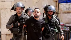 Las fuerzas de seguridad israelíes detienen a un hombre en la entrada de la mezquita al Aqsa este viernes.