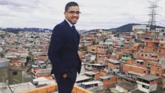 Um jovem sorridenteroleta de verdade e desafioterno e óculosroleta de verdade e desafiofrente à diversas casasroleta de verdade e desafiocomunidade