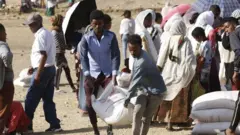 በትግራይ ሰዎች በአሜሪካ ተራድኦ ድርጅት የሚካፋፈል የእርዳ ምግብ ሲወስዱ