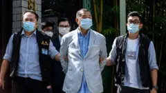 Police lead Hong Kong pro-democracy media mogul Jimmy Lai (C) away from his home