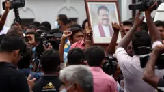 Des partisans pro-gouvernementaux tiennent le portrait du Premier ministre Mahinda Rajapaksa lors d'une manifestation devant la résidence du Premier ministre, tandis que des personnes filment et prennent des photos