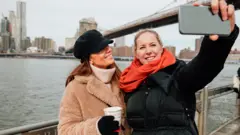 Stock image of two women taking a selfie in New York City, next to Brooklyn Bridge