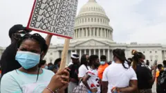 A young protester holds up a sign saying "Black Lives Matter" near the US Capitol in Washington (6 June 2020)