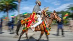 A man is seen riding a horse. Bother are wearing green, yellow and red colours for their symbolism.