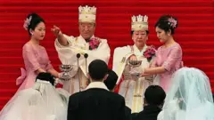 SEOUL, SOUTH KOREA - FEBRUARY 13: Sun Myung Moon (2nd L), founder of the Unification Church, and his wife (2nd R) bless the brides and the grooms in a mass wedding ceremony at Chamsil Olympic Stadium in Seoul 13 February 2000. Unification Church founder Moon married some 60,000 of his believers, many renewing their vows. AFP PHOTO (Photo credit should read PARK MEE-HYANG/AFP via Getty Images)