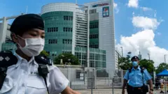 一名女警官（左）在香港將軍澳壹傳媒集團暨香港《蘋果日報》總部大樓門前拉起封鎖線（17/6/2021）