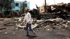 Men walk past shells on the ground near damaged buildings at the central market during clashes between the paramilitary Rapid Support Forces and the army in Khartoum North, Sudan April 27, 2023